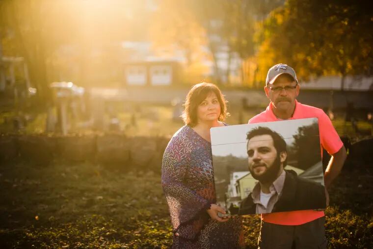 In this Nov. 8, 2018 photo, Janel Wentz and Tim Firestone pose for a photograph in Port Carbon, Pa. while holding an image of their late son former Mount Carbon Mayor Brandon Wentz. Wentz's family is speaking out for the first time about his sudden death one year ago. Wentz was 22 when he became mayor of Mount Carbon, population 87. He died suddenly last November at age 24, just hours after resigning from office due to a family move. Wentz's family says he died of an overdose of heroin and fentanyl. His passing came near the end of a year that saw a record number of drug overdose deaths. (AP Photo/Matt Rourke)