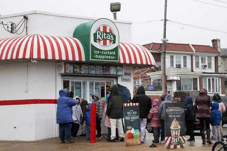 Customers wait in line amid snow and freezing rain for free ice to celebrate the first day of spring at Rita&#039;s Water Ice in Olney on Tuesday, March 20, 2018.