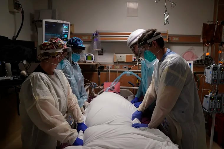 In this Dec. 22 photo, medical workers prepare to manually prone a COVID-19 patient in an intensive care unit at Providence Holy Cross Medical Center in the Mission Hills section of Los Angeles.