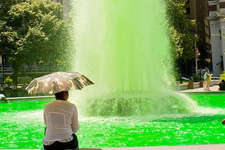Janice Pickney, 51, cools off as the LOVE Park fountain goes green. (LUIS FERNANDO RODRIGUEZ / Staff Photographer)