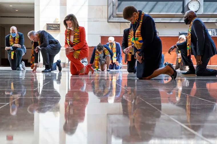 House Speaker Nancy Pelosi of Calif., center, and other members of Congress gather Monday at the Emancipation Hall, kneel and observe a moment of silence to honor George Floyd and victims of racial injustice.