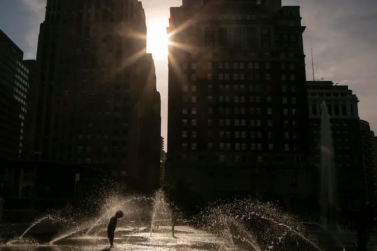 Kids are silhouetted as they play in the water fountain at LOVE Park amid a heatwave earlier this summer.