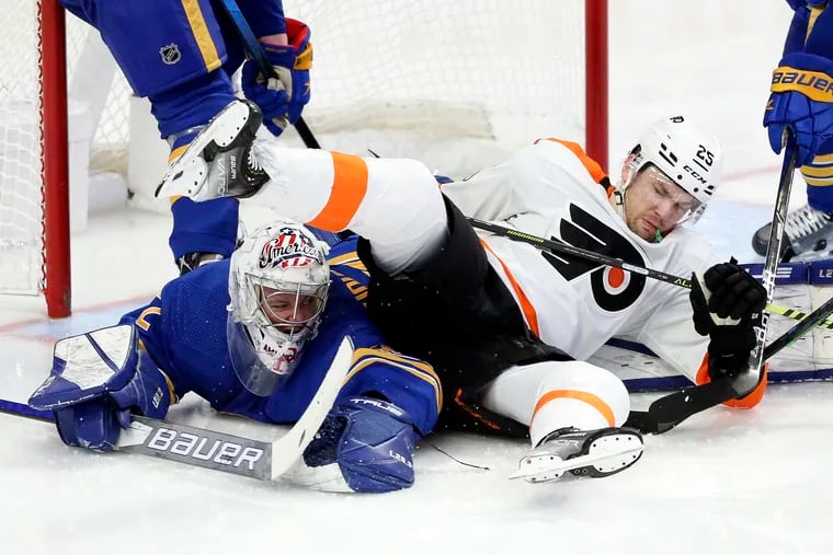Philadelphia Flyers left wing James van Riemsdyk (25) falls on Buffalo Sabres goaltender Michael Houser after attempting a shot during the third period of an NHL hockey game Saturday, Jan. 22, 2022, in Buffalo, N.Y. (AP Photo/Joshua Bessex)