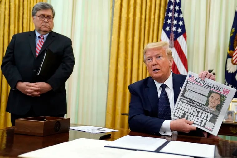 President Donald Trump (right) holds up a copy of the New York Post with a cover story about fact-checkers of his tweets as Attorney General William Barr looks on.