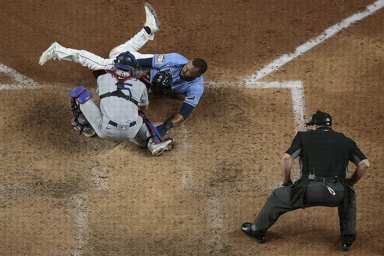 The Tampa Bay Rays' Manuel Margot (top) is tagged out by Los Angeles Dodgers catcher Austin Barnes on an attempted steal of home in the fourth inning during Game 5 of the World Series at Globe Life Field in Arlington, Texas, on Sunday, Oct. 25, 2020.