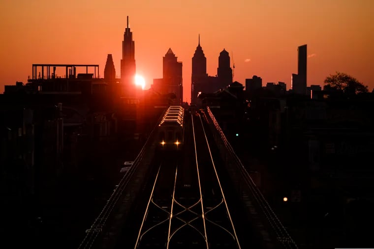 A train heads west as the sun rises from behind the city skyline in Philadelphia, Wednesday, March 6, 2019.