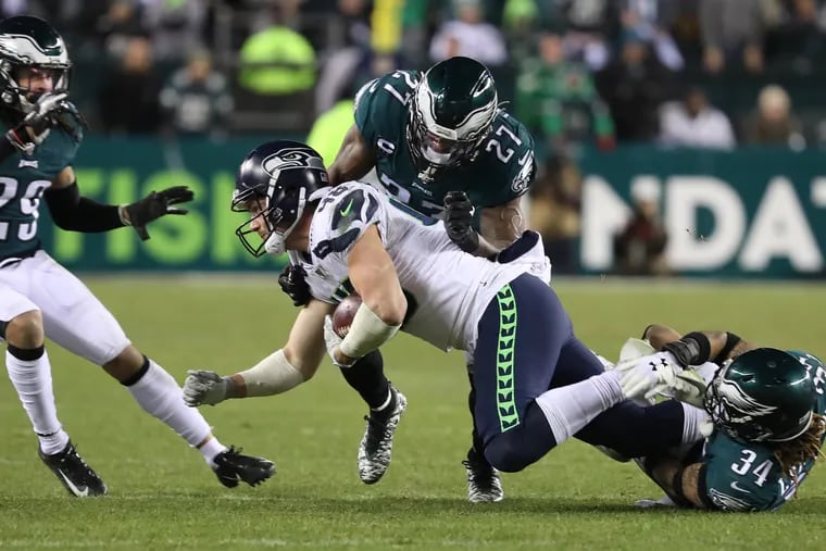 Seattle tight end Jacob Hollister is brought down by Eagles defenders, Avonte Maddox (left) Malcolm Jenkins (center) and Cre’Von LeBlanc (right) during the third quarter.