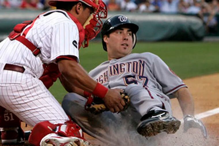 Phillies catcher Carlos Ruiz tags out Nationals starting pitcher Jason Bergmann at the plate. A half-inning later, Bergmann left the game with a hamstring injury.