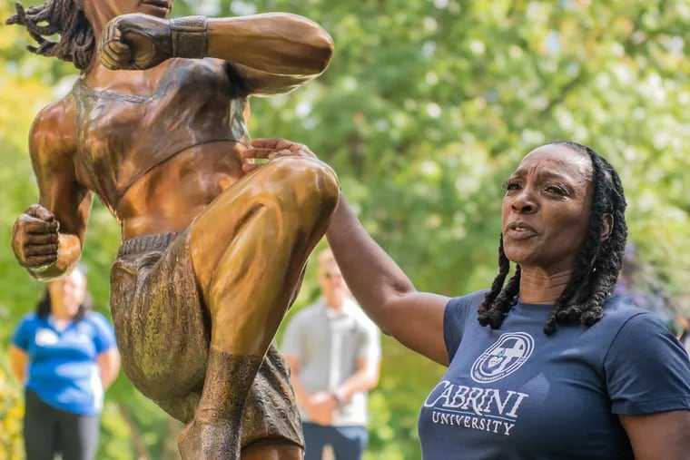 Chester's Fredia Gibbs, the first Black woman to hold the International Sport Kickboxing Association (ISKA) world kickboxing title, stands next to a bronze statue of herself on the campus of Cabrini University on Wednesday, Sept. 28, 2022.