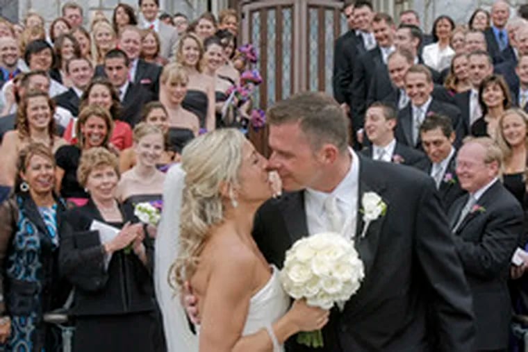 Tara Lanee DeSorbo and Richard Thomas Simpson kiss in front of the St. Thomas of Villanova Church and their delighted guests after their wedding ceremony.