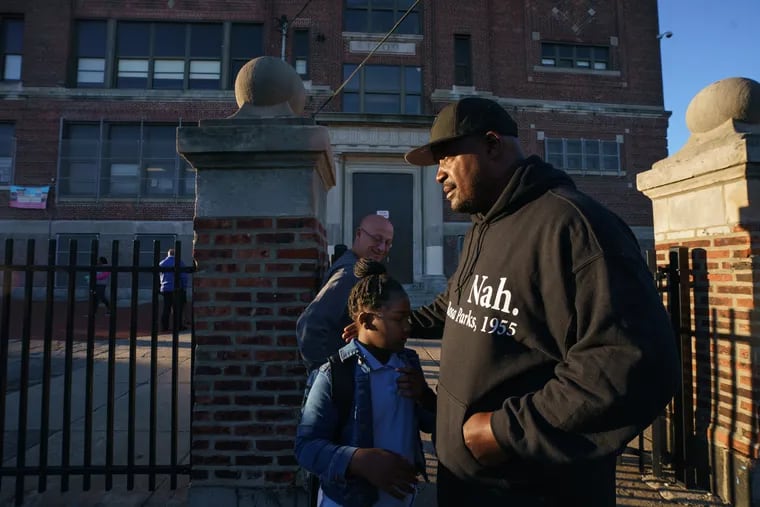 Antoine Little, an advocate and parent of three children at Thomas M. Peirce School, is shown outside the school in this file photo with his 9-year-old daughter, Najah Little. Parents on Monday said they would not send their children back to the school until damaged asbestos was removed.