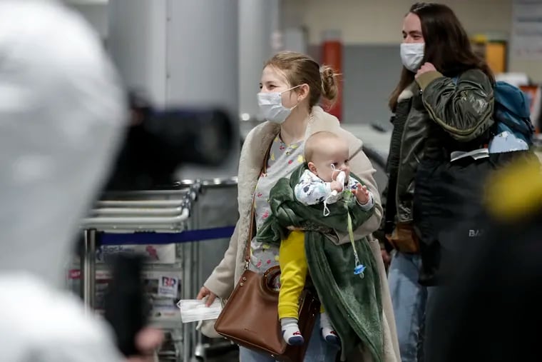 A woman with her baby walks to medical experts to be checked for coronavirus infection after arriving at an airport outside Moscow.