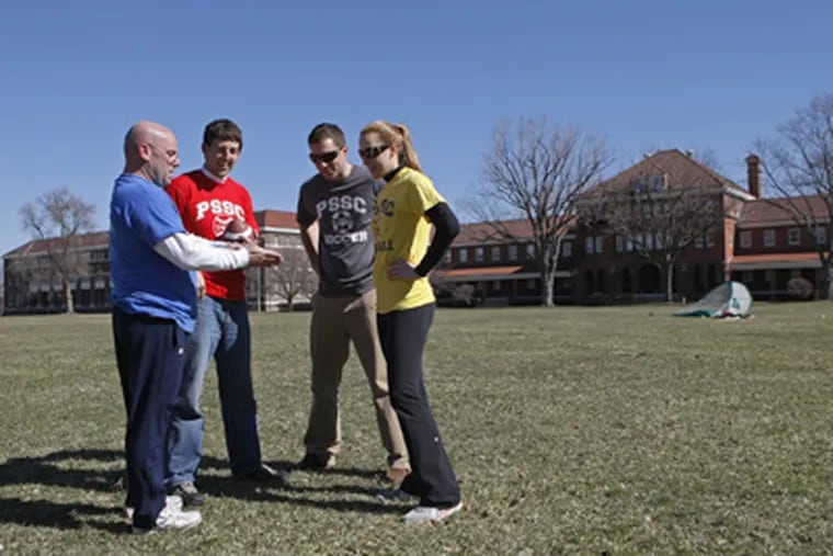 From left, Tim Horan, Dan Feeney, Eric Long, and Amy Feeney discuss a football play on the Navy Yard's Marine Parade Ground. (Michael S. Wirtz / Staff Photographer)