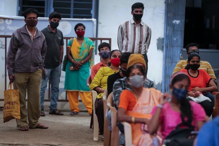 People wait to receive the vaccine for COVID-19 at a vaccination center set up at a government run school in Bengaluru, India, Tuesday, Sept. 21, 2021.