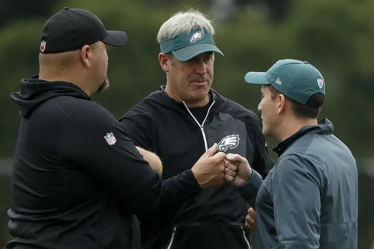 Eagles coach Doug Pederson, center, giving Howie Roseman a fist bump during training camp in August.