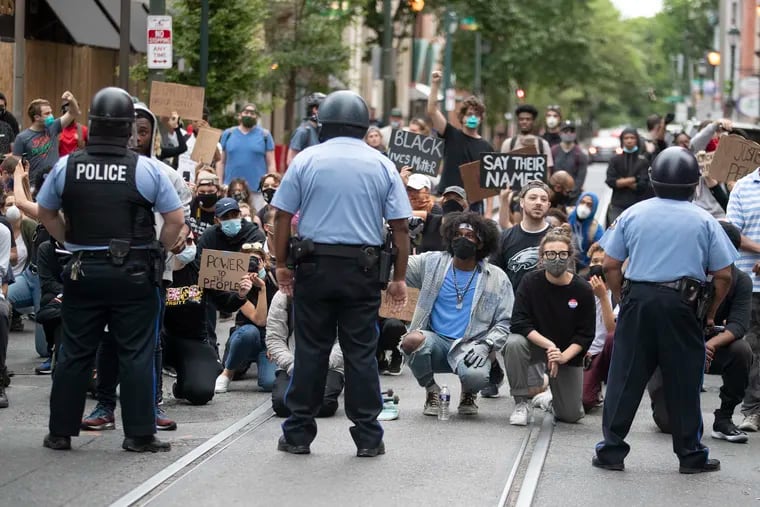 Protesters take a knee on Walnut Street in front of a row of police officers during a Justice For George Floyd protest on June 2, 2020.
