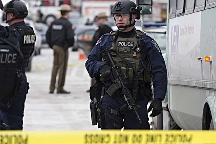 A heavily armed police officer walks on scene after a shooting at The Mall in Columbia on Saturday, Jan. 25, 2014 in Columbia, Md. Police say three people died in a shooting at the mall in suburban Baltimore, including the presumed gunman. (AP Photo/ Evan Vucci)