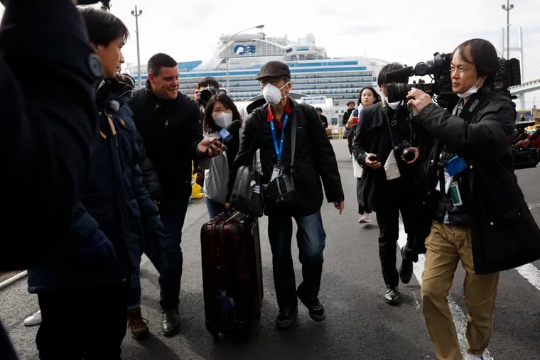 An unidentified passenger is surrounded by the media after he disembarked from the quarantined Diamond Princess cruise ship Wednesday, Feb. 19, 2020, in Yokohama, near Tokyo. Passengers tested negative for COVID-19 started disembarking Wednesday.