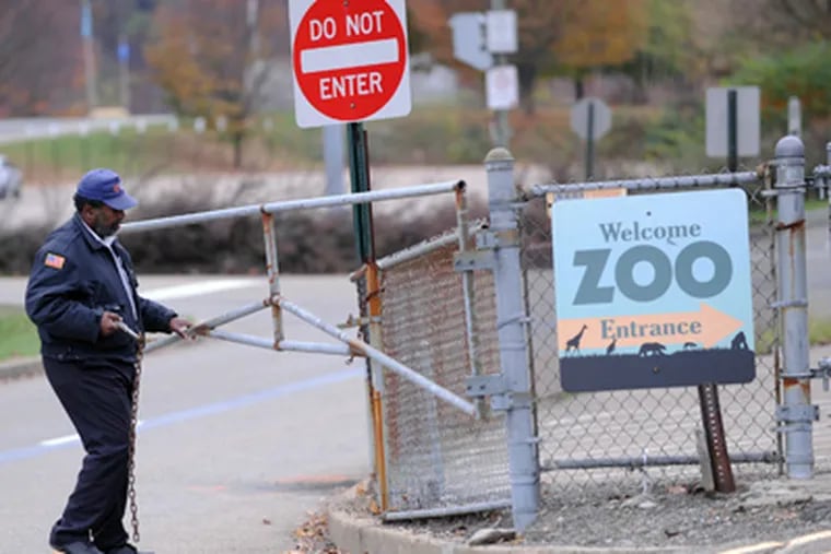 A security guard closes the gate at the Pittsburgh Zoo, where zoo officials say a young boy was killed after he fell into the exhibit that was home to a pack of African painted dogs, who pounced on the boy and mauled him, Sunday, Nov. 4, 2012. (AP Photo/John Heller)