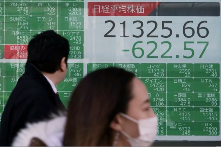 People walk past an electronic stock board showing Japan's Nikkei 225 index at a securities firm in Tokyo on Friday.
