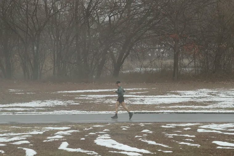 A jogger runs along melted snow at FDR Park in South Philadelphia earlier this month. Snow is due to make a modest comeback on Sunday..