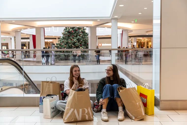 Two shoppers sitting with their bags of purchased items during Black Friday at the King of Prussia Mall on Friday, Nov. 25, 2022.