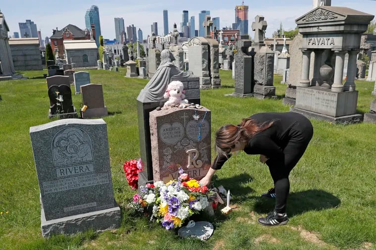 In this May 10, 2020 photo, Sharon Rivera adjusted flowers and other items left at the grave of her daughter, Victoria, at Calvary Cemetery in New York, on Mother's Day. Victoria had died of a drug overdose on Sept. 22, 2019, when she just 21 years old.
