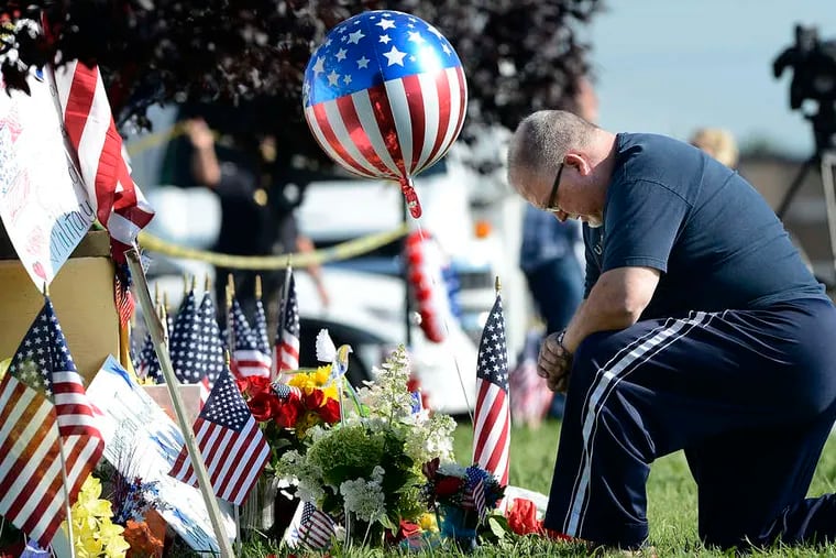 Bill Lettmkuhl kneels by a makeshift memorial Friday in front of a military site that was part of a shooting rampage on Thursday that left four Marines dead in Chattanooga, Tenn.