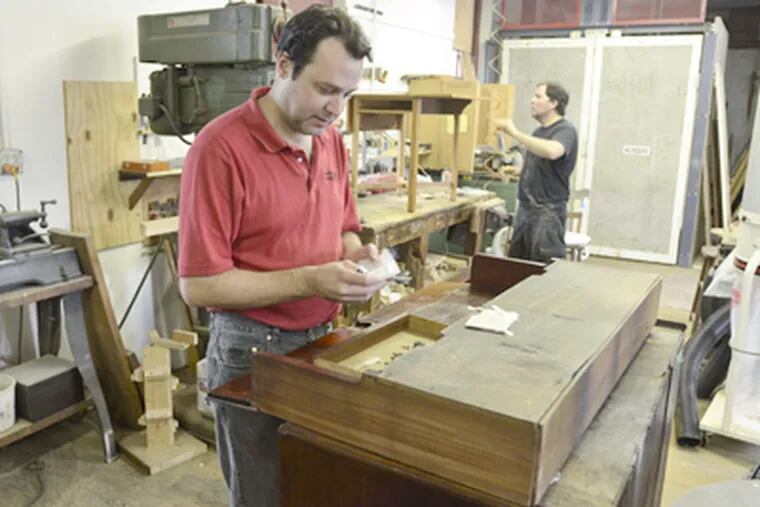 John Hutchinson, owner of Rose Valley Restorations, works on a piece of furniture in his workshop. In the background is Steve Swann. (Ron Tarver / Staff Photographer)