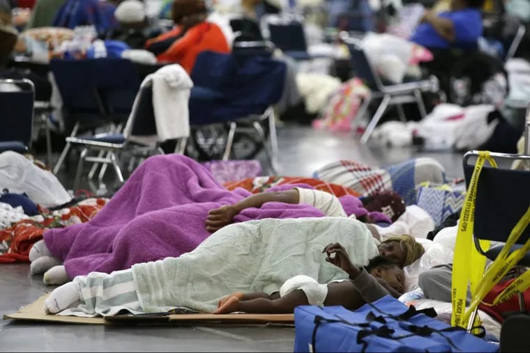 People sleep on the floor at the George R. Brown Convention Center that has been set up as a shelter for evacuees escaping the floodwaters from Tropical Storm Harvey in Houston, Texas, Tuesday, Aug. 29, 2017. (AP Photo/LM Otero)