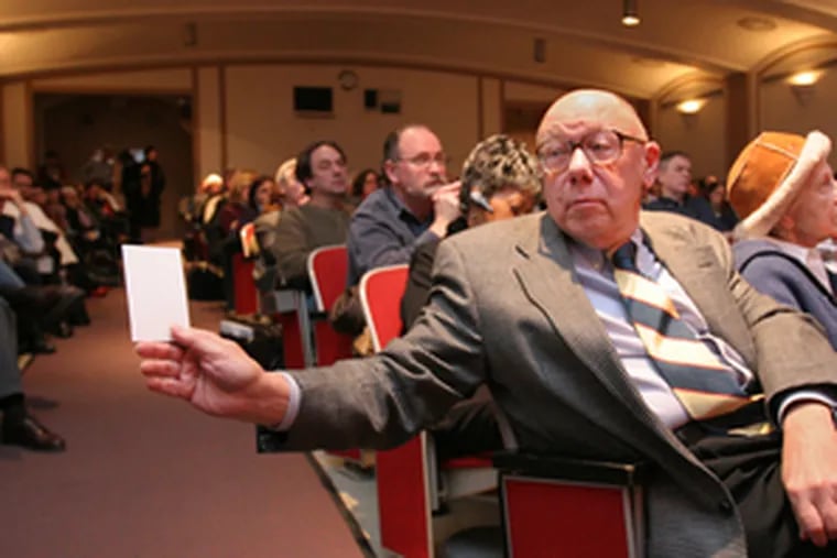 Tully Speaker of Center City holds out an index card on which he had written a question for the three mayoral candidates present.