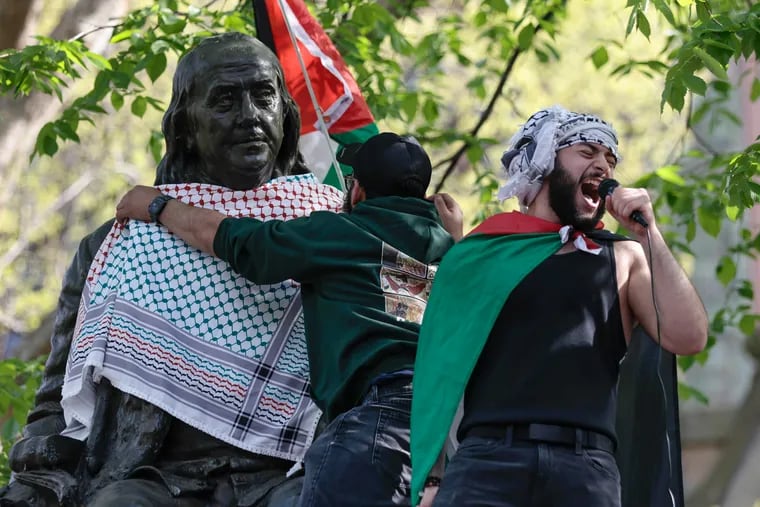 Qais Dana of Philadelphia shouts protest chants as a person puts a scarf on a Ben Franklin statue on Penn’s campus as part of a pro-Palestine demonstration in Philadelphia on Thursday, April 25, 2024