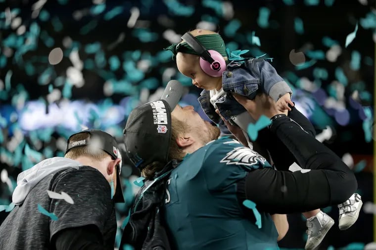 Eagles' Nick Foles lifts his daughter, Lilly, right, after the Philadelphia Eagles win 41-33 over the New England Patriots in the Super Bowl in Minneapolis, MN on February 4, 2018. DAVID MAIALETTI / Staff Photographer