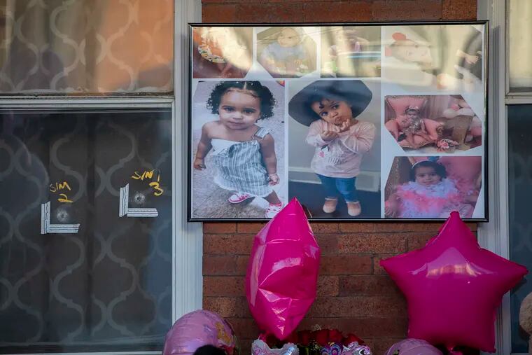 A collection of photographs of Nikolette Rivera, the 2-year-old who was shot and killed, hangs on the front porch of the family home next to the marked entry of two bullet holes that went through the front window of the home on Sunday.