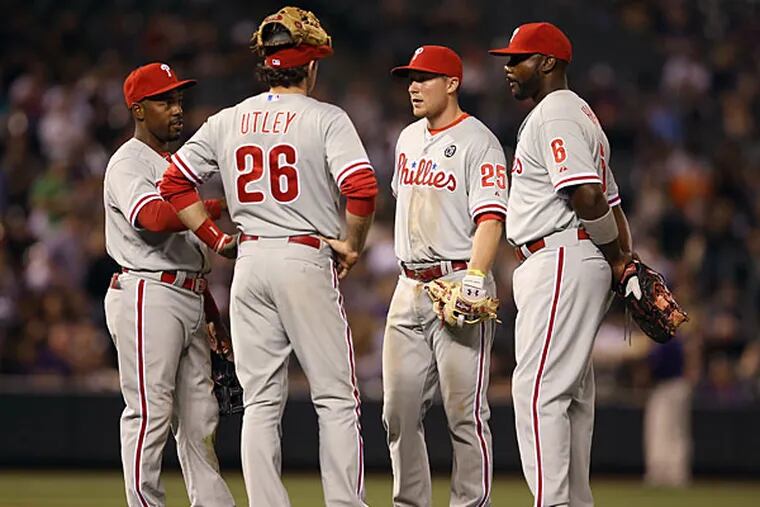 Infielders Jimmy Rollins #11, Chase Utley #26, Cody Asche #25 and Ryan Howard #6 of the Philadelphia Phillies of the Philadelphia Phillies await a pitching change in the seventh inning at Coors Field on April 18, 2014 in Denver, Colorado. (Photo by Doug Pensinger/Getty Images)