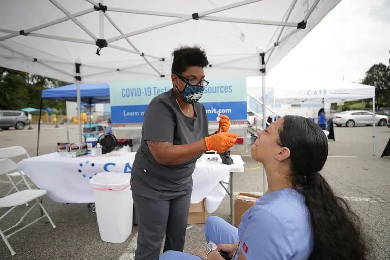 Chrystal Handford (left) gives a COVID-19 test to Ashley Latimer at the Community Accessible Testing & Education truck in the parking lot at Concilio in Philadelphia on Sept. 27. The state's traveling truck conducts COVID-19 testing on-site.
