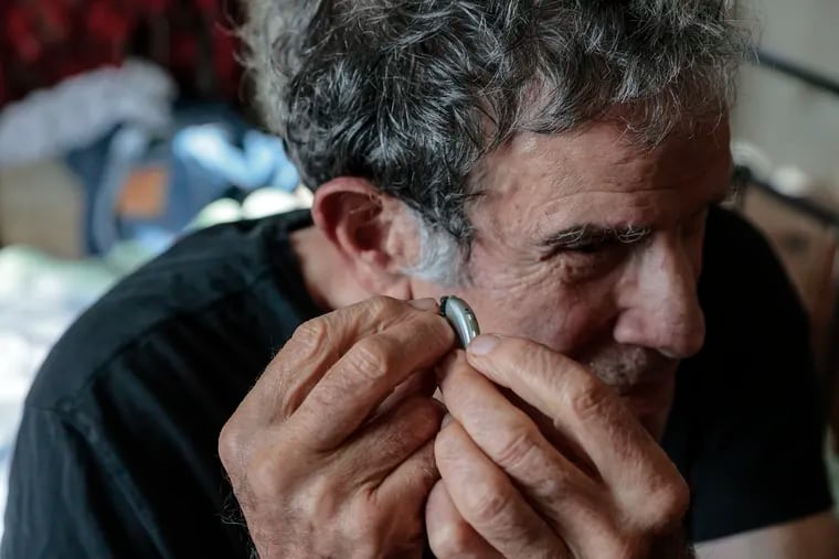 Paul Jablow puts in his hearing aids at home on Tuesday.