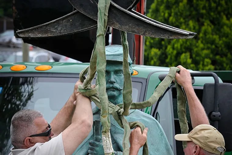 Willie Farrell, who carved the base for the "Silent Sentry," and Frank Rausch prepare the statue to be lifted in place at Laurel Hill Cemetery May 14, 2014. ( RON TARVER / Staff Photographer )
