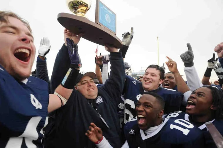 West Catholic coach Brian Fluck (above) holds aloft the state championship trophy as his players cheer him on. West quarterback Anthony Reid (below) scores a second-quarter TD.