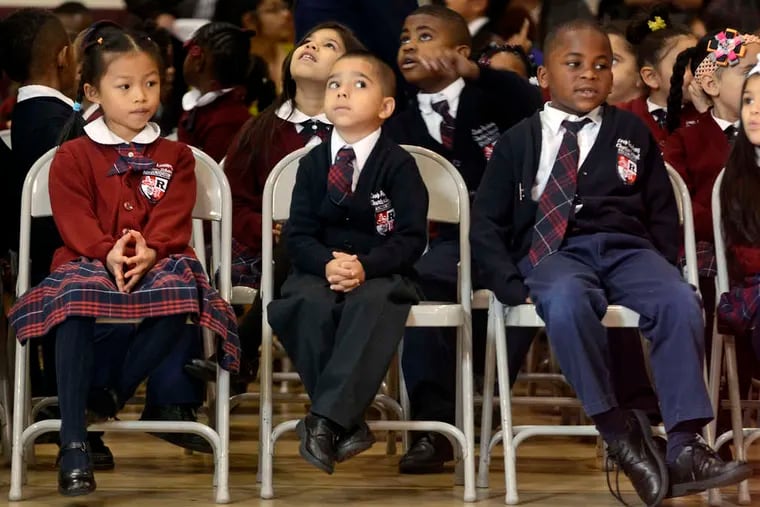 In this file photo, LEAP Academy University Charter School first graders (from left) Angelina Le, Angel Rivera, and Amir Reason-Dallas await ceremonies inducting them into a scholarship program.