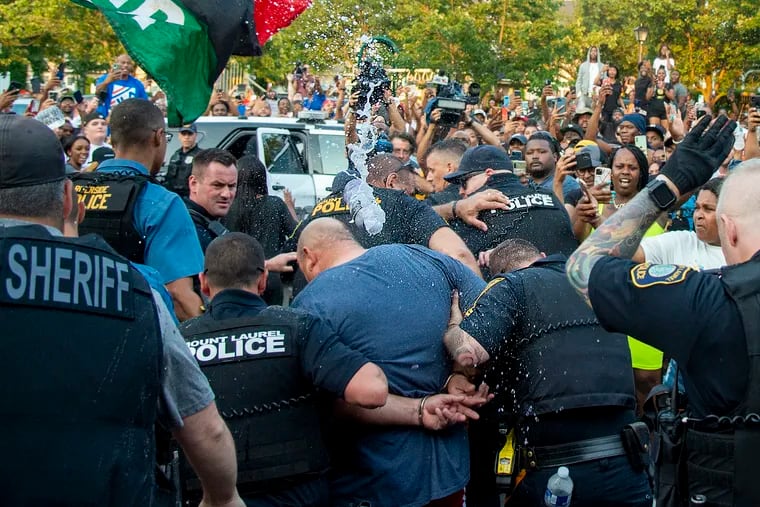 Edward Cagney Mathews is pummeled with water bottles as he is escorted by police through a crowd of protesters on July 5. Protesters gathered outside his Mount Laurel home after a video went viral showing Mathews shouting racial slurs and offensive language at his neighbors.