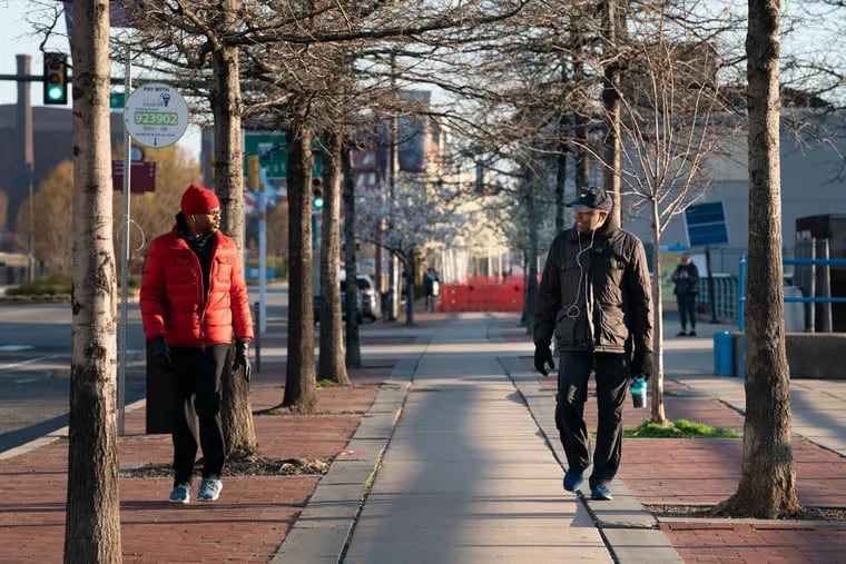 Quentin Heyward (left) and Martini Shaw walk together while keeping their distance at Race Street Pier on March 26. Friends who worked out at the same gym before the coronavirus pandemic, they now walk at sunrise and sunset.