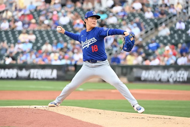 Yoshinobu Yamamoto #18 of the Los Angeles Dodgers delivers a warm up pitch against the Texas Rangers during a spring training game at Surprise Stadium on February 28, 2024 in Surprise, Arizona.