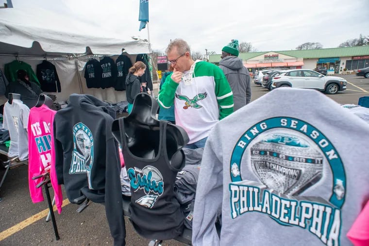 Lee Levin looks over Eagles shirts and sweatshirts at a stand Sunday on York Road in Hatboro. Hours before the Super Bowl, Eagles fans throughout the region were still shopping for something green to wear during the game.