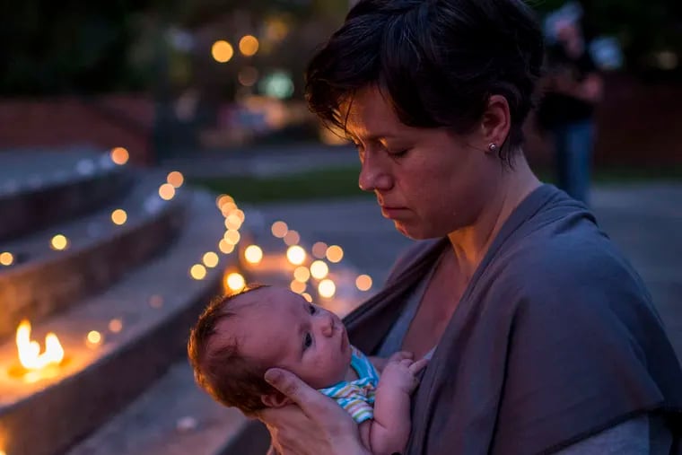 Kate Lemoine holds her daughter, Harlan Hawkins, during a vigil for the victims. PAUL KIEU / (Lafayette, La.) Daily Advertiser