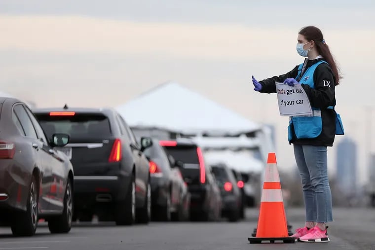 Philadelphia Medical Reserve Corps volunteer Emma Ewing, a sophomore at Temple University, directs cars at the city's coronavirus testing site next to Citizens Bank Park in South Philadelphia.
