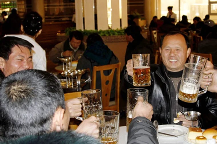 North Koreans hoist their beer glasses after hearing the news of a successful rocket launch. KIM KWANG HYON / AP
