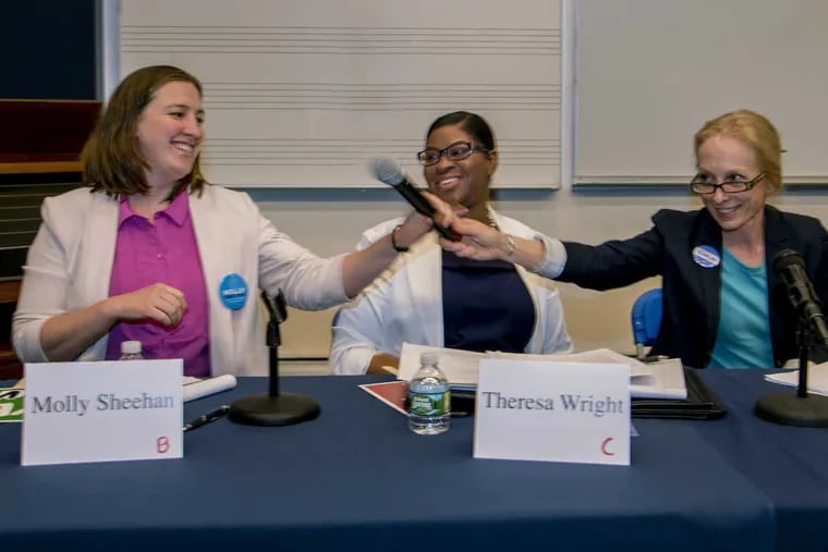 Democratic Fifth Congressional District primary candidates (from left) Molly Sheehan, Theresa Wright, and Mary Gay Scanlon pass the shared microphone across the table to next speaker during their debate at Cabrini University  May 1, 2018.