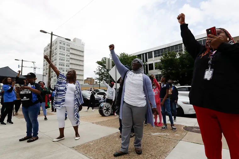 Demonstrators raise their fists at the end of a rally in opposition to the closing of Black-led charters at the School District of Philadelphia Headquarters on Thursday, June 23, 2022.