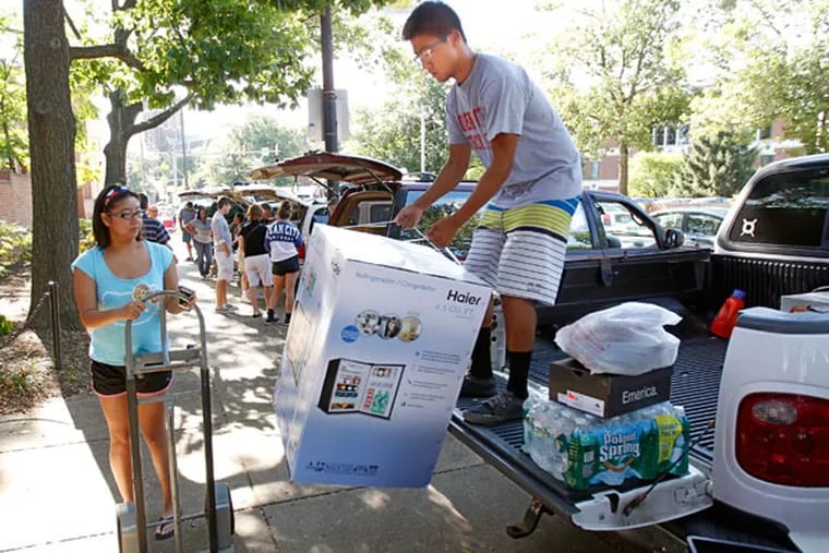 Eric Lam, a freshman at La Salle, unloads his dorm room refrigerator from the back of his truck while Andrienne Lam waits with the cart. (Michael Bryant/Staff Photographer)
